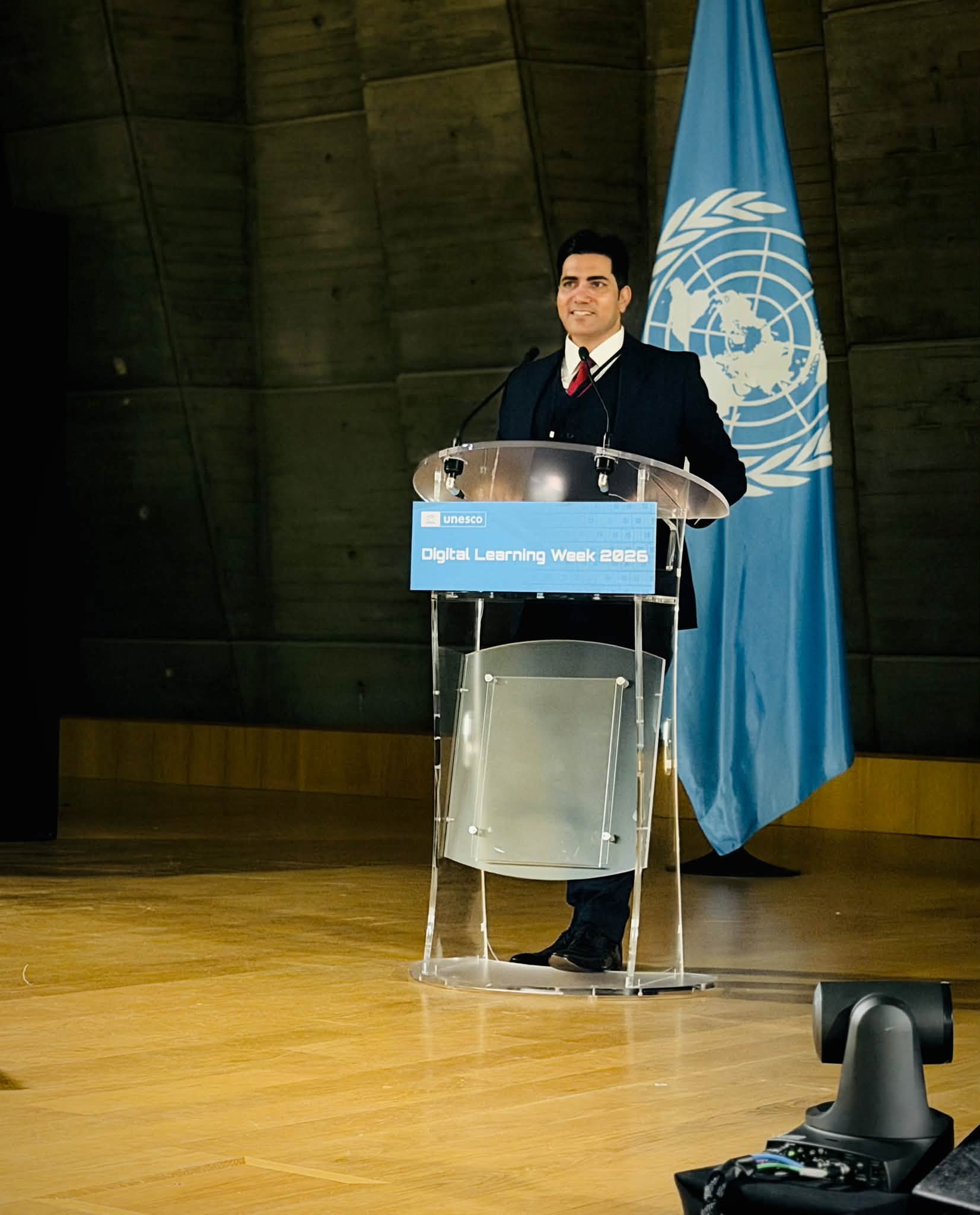 Rizwan Anwar speaking at the UNESCO Digital Learning Week 2026 podium beside the UN flag at UNESCO Headquarters, Paris
