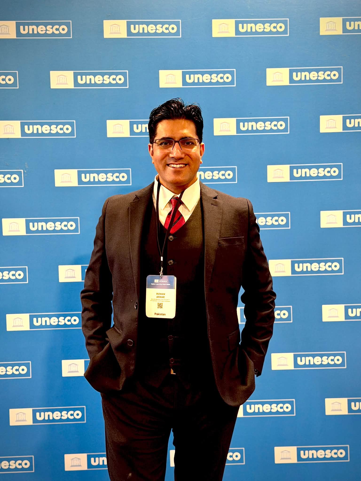 Rizwan Anwar wearing his Pakistan delegate badge in front of the UNESCO backdrop at Digital Learning Week 2026, Paris